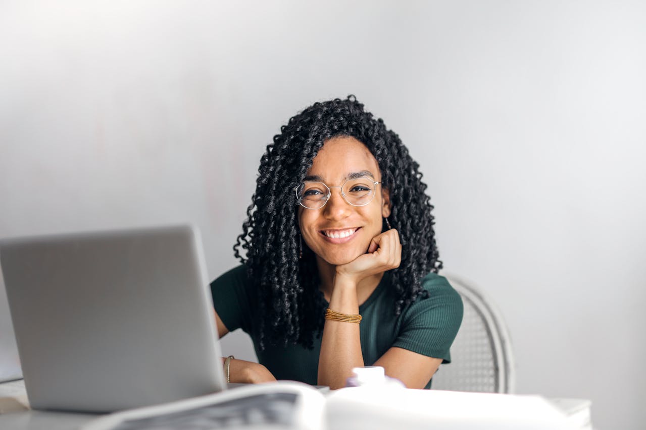 Black lady smiling and learning online on her laptop.